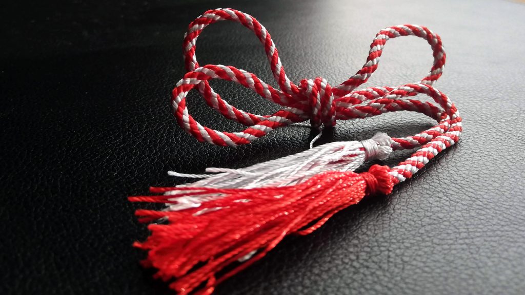Image depicting a traditional red and white twined thread with tassels.